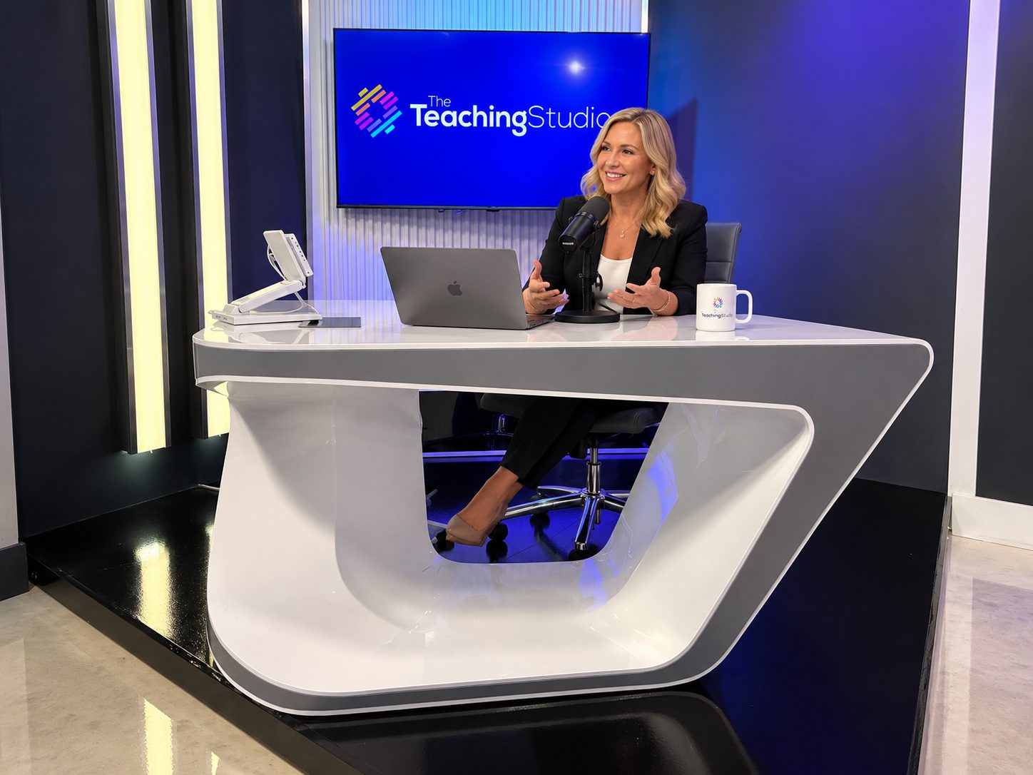 The teaching desk with a laptop, microphone and branded screen